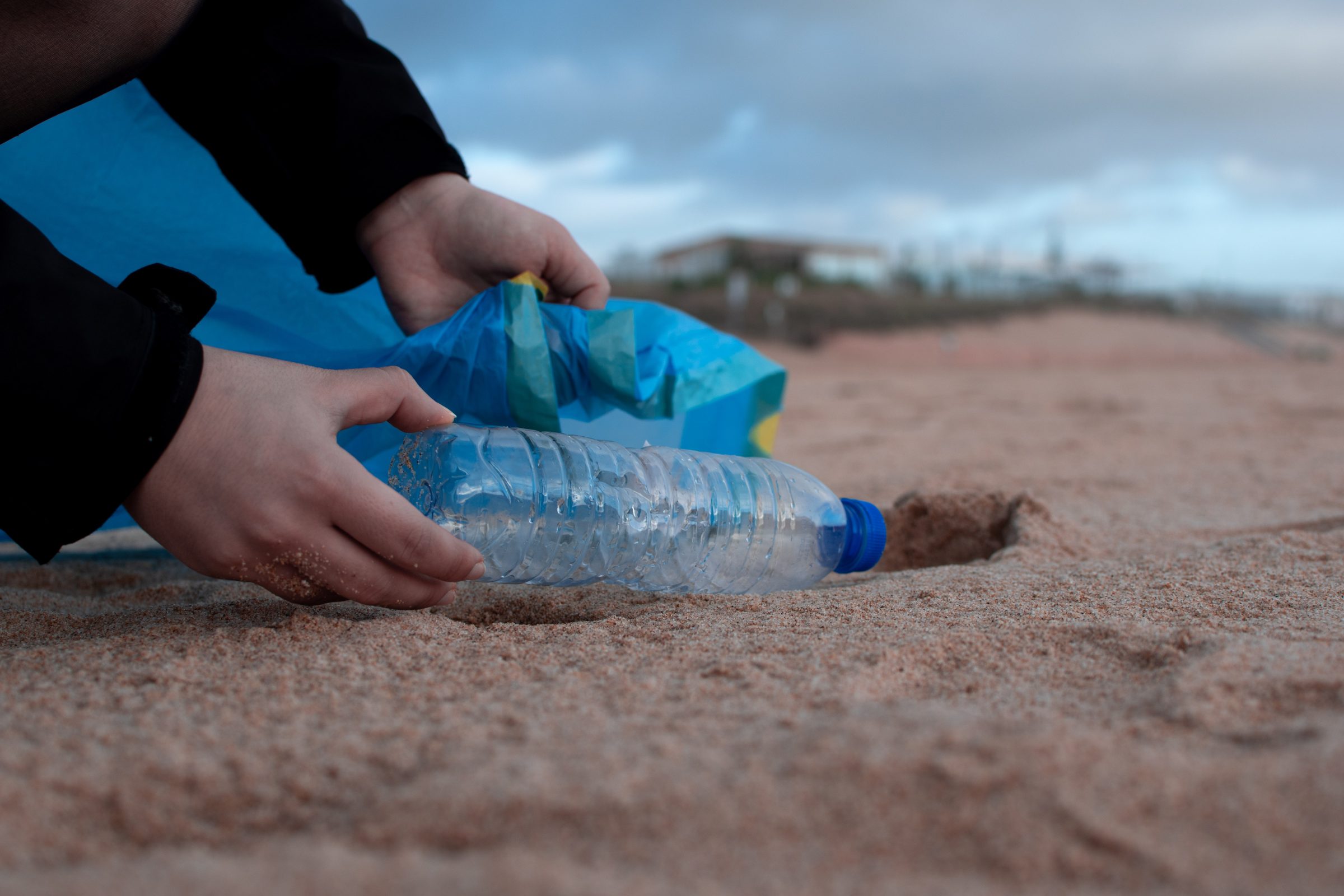 Picking up a bottle of rubbish on a beach