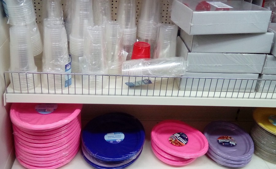 A supermarket shelf with plastic plates and cups