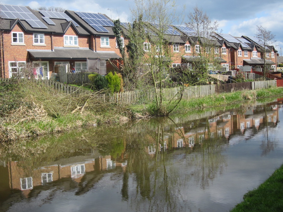 A image across a canal with a row of houses on the furthest bank